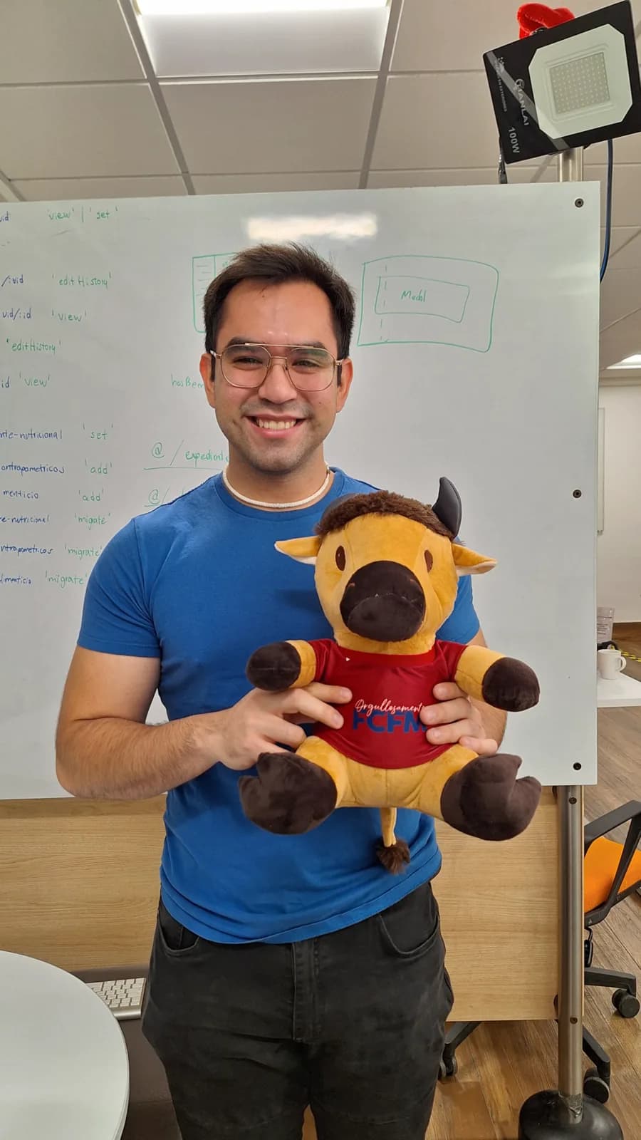 Arturo holding the FCFM mascot in front of a whiteboard covered in API route sketches
